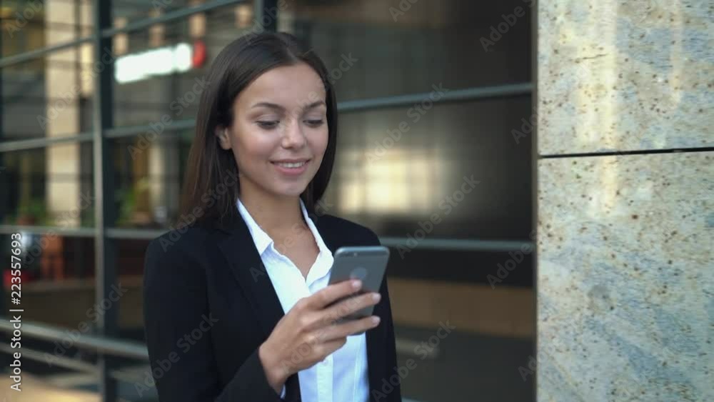 Cheerful young girl walking in downtown and reading on smartphone Cheerful young girl walking in downtown and reading on smartphone