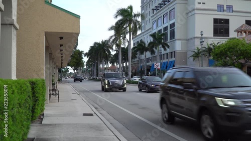Day time exterior establishing street view shot of downtown Boca Raton florida. Busy traffic drives by past stores and business buildings
