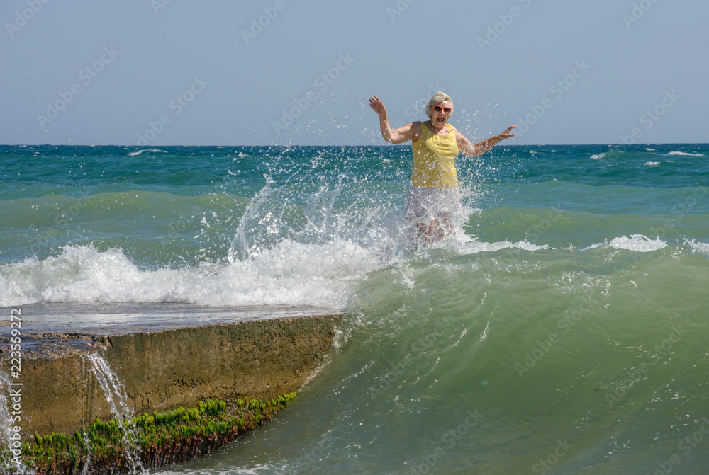 Woman cried out in surprise of splashing waves on groyne. Woman cried out in surprise of splashing waves on groyne.