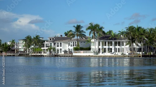 Establishing shot of generic luxury vacation mansion homes along coastal water way during beautiful summer day time. Exterior lock down view in 4K along shore line.