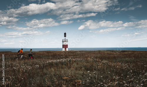 A girl and a lonely red-white lighthouse in an autumn field on the shores of the Okhotsk Sea in the north of the Khabarovsk Territory of Russia