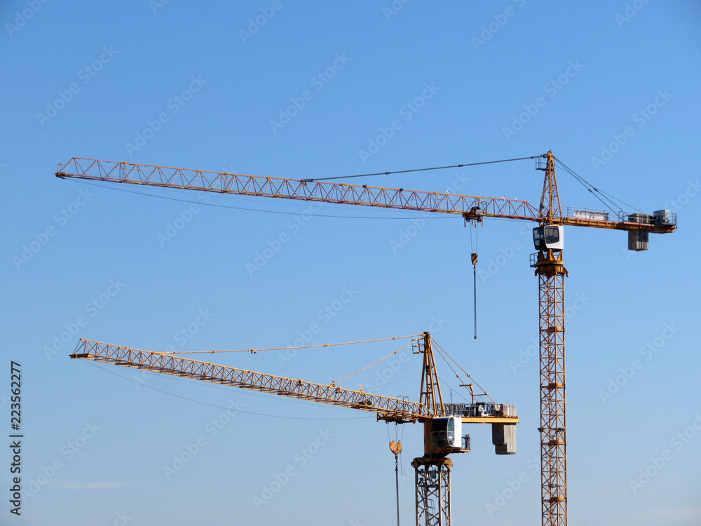 Yellow construction cranes isolated on clear blue sky background