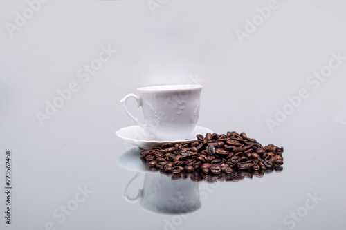 White cup with coffee. Coffee beans. Reflection in the mirror.