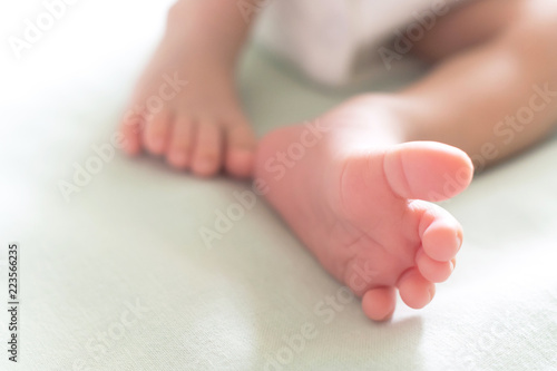 little tiny feet and toes of happy newborn baby sleeping in the baby bed in the morning sunlight. family and healthy baby concept. selective focus and soft tone photo. © gumpapa
