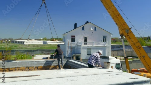 A man directs a concrete slab on the roof of the building