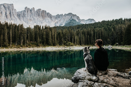 Frau sitzt mit Hund auf einem Felsen am Karersee photo