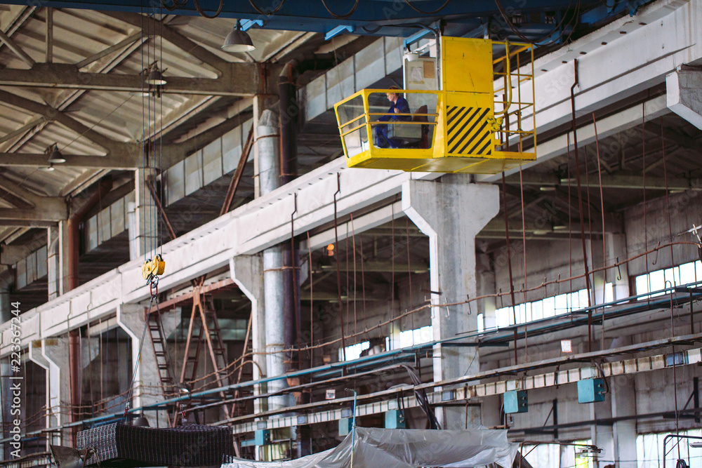 The girl working in the cab of a crane. Heavy industry, metal factory.