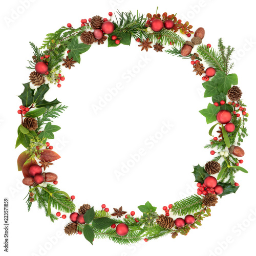 Traditional  winter and Christmas wreath garland with natural flora and fauna and red bauble decorations on white background. Christmas card for the festive season.