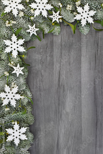 Christmas and winter snowflake, star and spruce fir with mistletoe background border on rustic grey wood background.