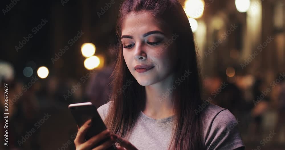 Young attractive woman using mobile phone on street of night town. Woman using mobile phone for business communication voice message Young attractive woman using mobile phone on street of night town. Woman using mobile phone for business communication voice message