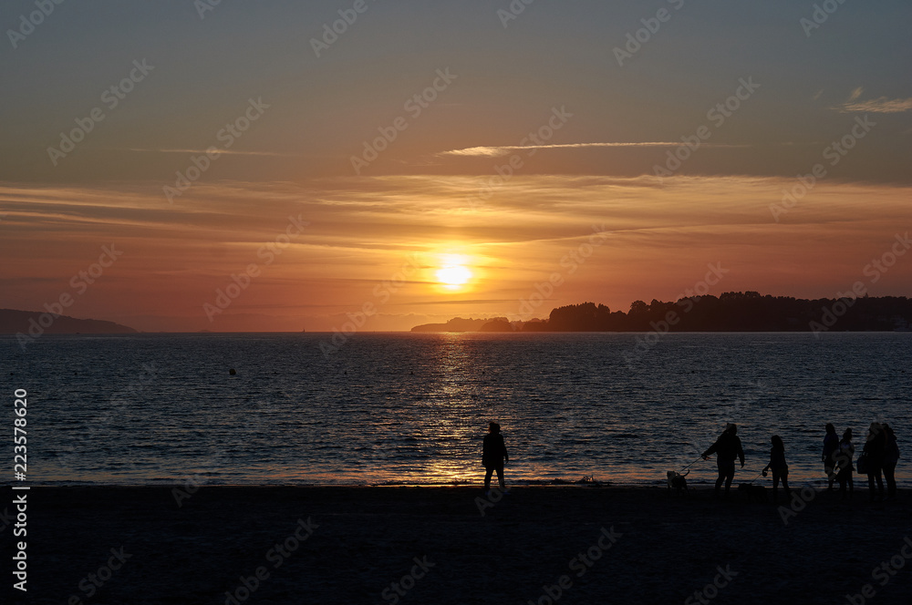 People on the beach at sunset. Silhouettes and colors