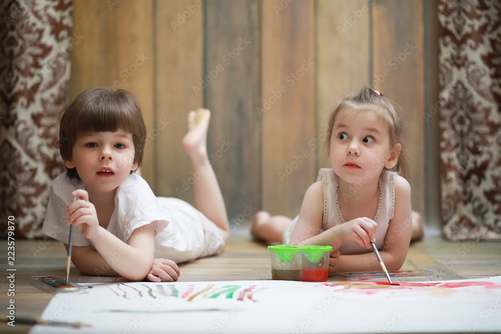 Little children paint on a large sheet of paper Little children paint on a large sheet of paper