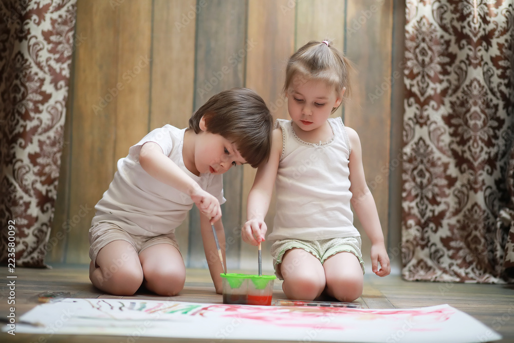 Little children paint on a large sheet of paper Little children paint on a large sheet of paper