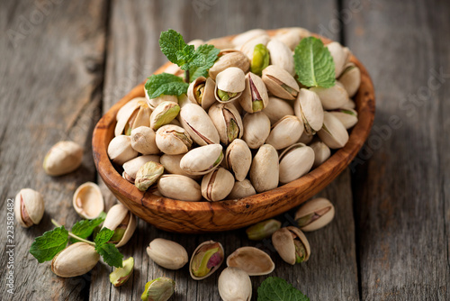 Bowl with pistachios on a wooden table.