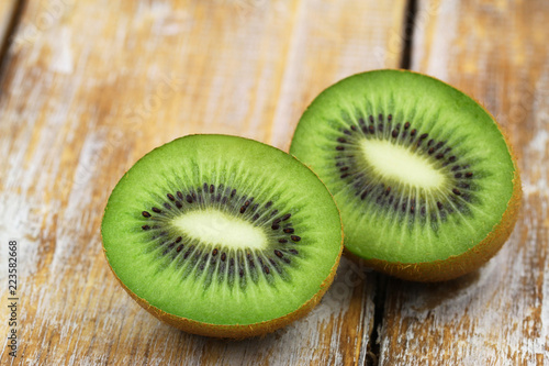 Closeup of two halves of fresh kiwi fruit on rustic wooden surface
