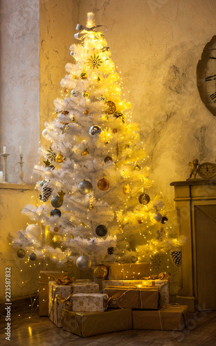 Interior of the new year. White Christmas tree, fireplace, chair and clock