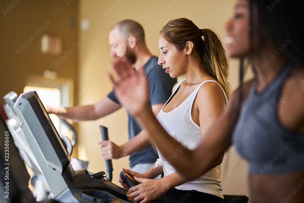 three people using treadmills in gym together