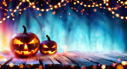 Halloween Party - Pumpkins And String Lights On Table In Dark Forest
