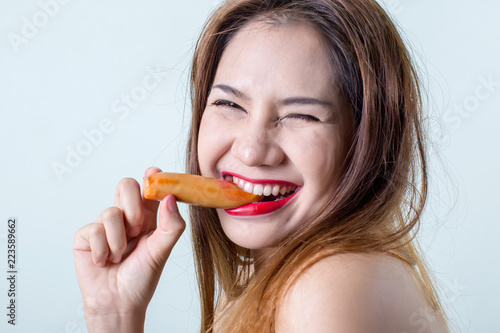Young woman eating sausage or hotdog. girl is sitting in the kitchen and greedily eats sausage. women eating sausage with hand lifestyle shot. girl eating meat sausage in the backyard