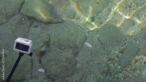 Man shooting video for home memories using action camera in waterproof case. Camera attached to black monopod. Real time full hd video footage.