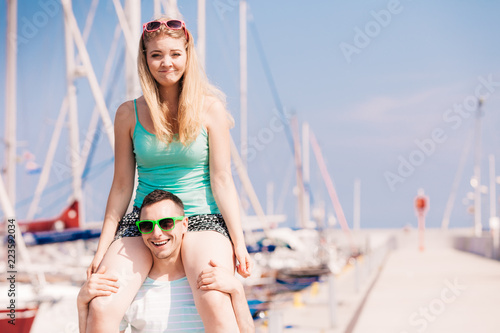 Man giving girlfriend piggyback ride on marina