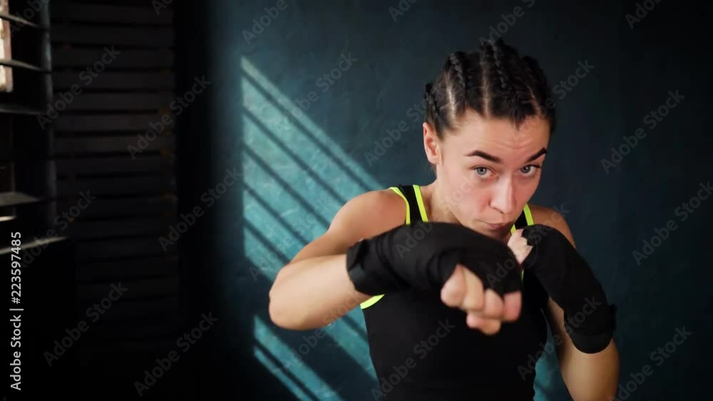 closeup portrait beautiful young boxing woman training punching in fitness studio. Fit female preparing to boxing competition. Wellness, fighting, motivation, martial arts, self defense concept closeup portrait beautiful young boxing woman training punching in fitness studio. Fit female preparing to boxing competition. Wellness, fighting, motivation, martial arts, self defense concept