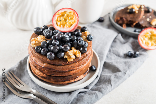 Stack of homemade chocolate pancakes with blueberries and chocol