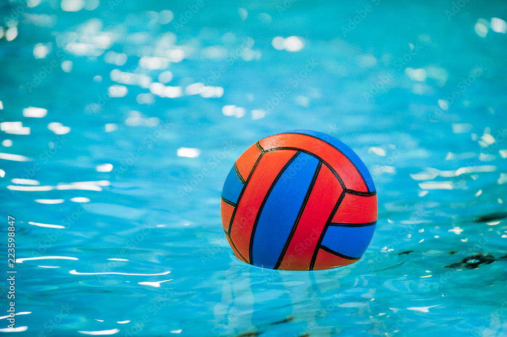 A water polo ball floating on the water in a pool.