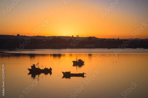 Sunrise in the harbour of Quellon in Chiloe Island, fishing boats silhouettes