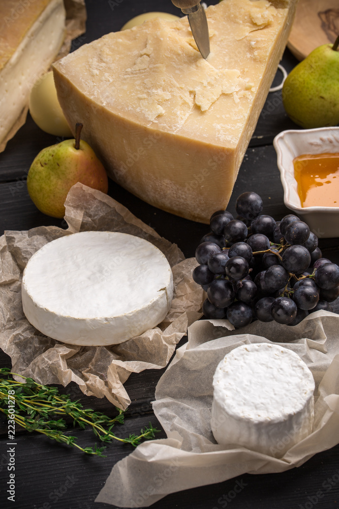 Parmesan and goat cheese with pears, grape and honey on dark wooden table Parmesan and goat cheese with pears, grape and honey on dark wooden table
