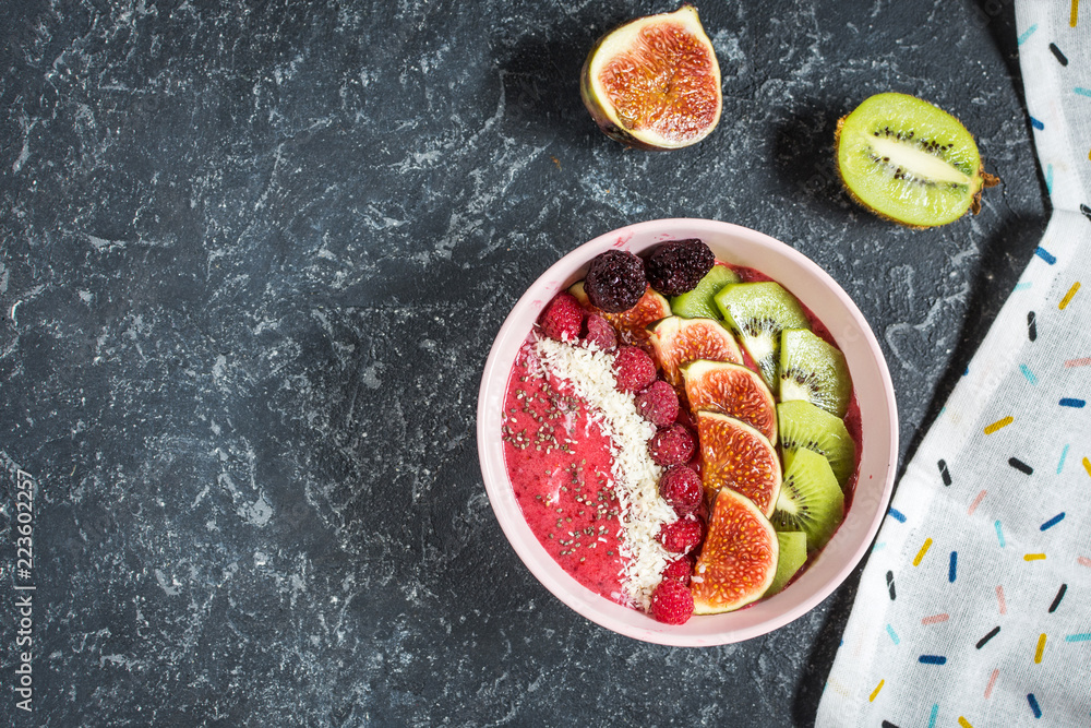 Raspberries smoothie bowl with figs, kiwi and coconut on concrete background Raspberries smoothie bowl with figs, kiwi and coconut on concrete background