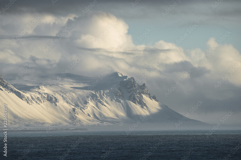 Scenic view of sea with snowcapped mountain against cloudy sky Scenic view of sea with snowcapped mountain against cloudy sky