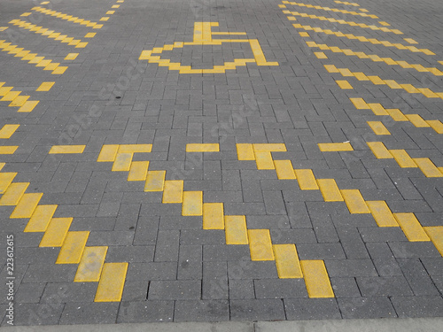 A designated handicap parking space outline in yellow brickwork 