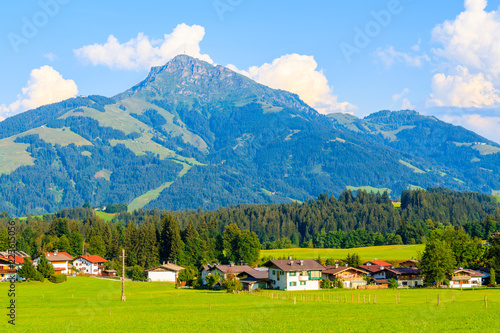 Houses on green meadow in Going am Wilden Kaiser village on sunny summer day against Alps mountains background , Tyrol, Austria