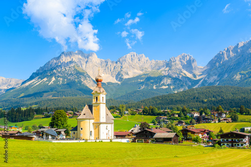 Church on green meadow in Going am Wilden Kaiser mountain village on sunny summer day, Tyrol, Austria photo
