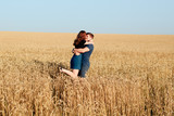 young loving couple in nature in summer on a background of field with oats