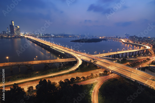 Aerial view of illuminated light trails on Mapo Bridge over Han River against blue sky at night photo