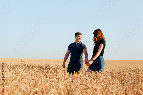 young loving couple in nature in summer on a background of field with oats