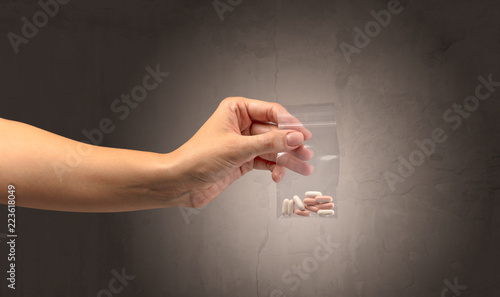 Naked, female hand giving drugs in plastic bag photo