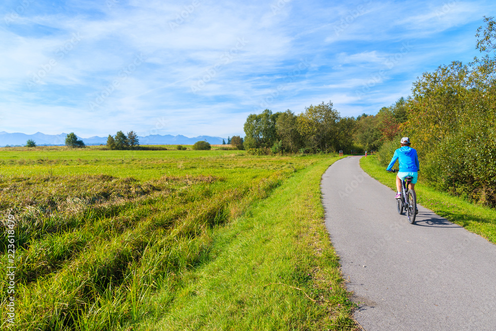 Young woman riding bike on cycling track around Tatra Mountains near Czarny Dunajec village. The end point is in Trstena village in Slovakia. Young woman riding bike on cycling track around Tatra Mountains near Czarny Dunajec village. The end point is in Trstena village in Slovakia.