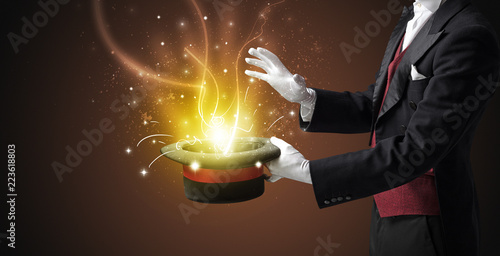 Magician hand conjure with wand  light from a black cylinder