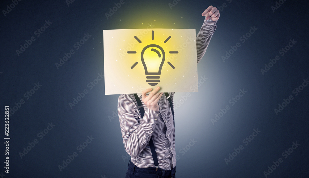 Young businessman hiding behind a lightbulb drawn on paper Young businessman hiding behind a lightbulb drawn on paper