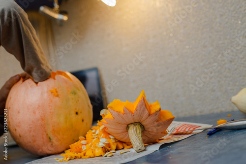 Child carves from a pumpkin. family fun activity. Сarved pumpkins into jack-o-lanterns for halloween. Carving big orange pumpkins for Halloween in late Autumn. photo