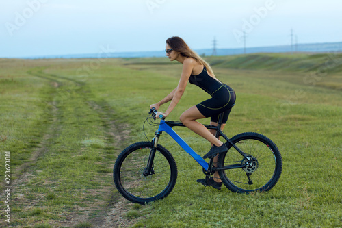 Girl on a mountain bike on offroad, beautiful portrait of a cyclist at sunset 