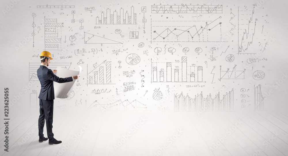 Engineer with construction helmet holding a plan and standing with graphs, charts and reports on the background Engineer with construction helmet holding a plan and standing with graphs, charts and reports on the background