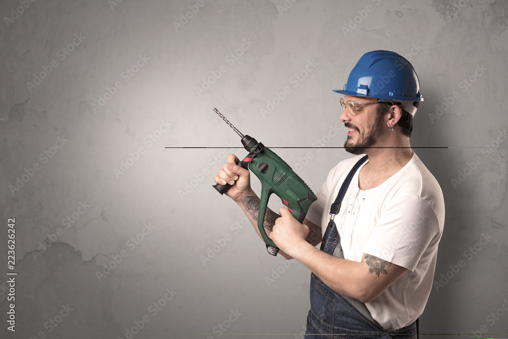 Craftsman standing in front of an empty wall with tool in his hand. Craftsman standing in front of an empty wall with tool in his hand.