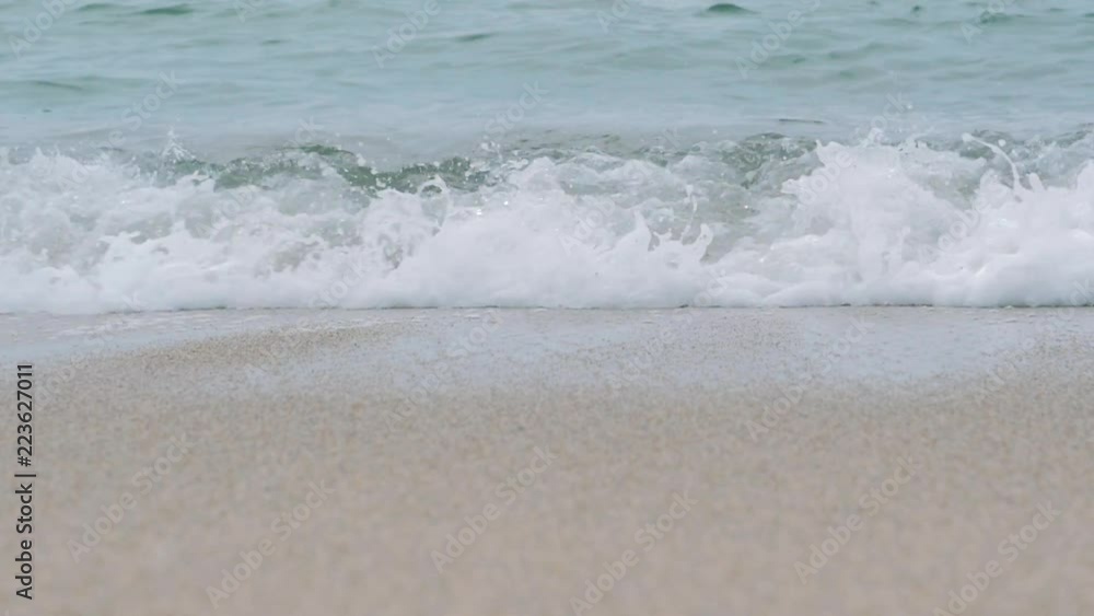 Sea waves crash over the sand beach on cloudy day Sea waves crash over the sand beach on cloudy day