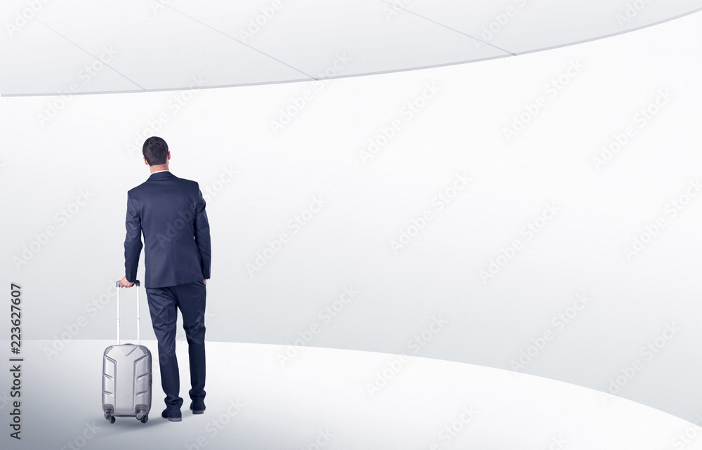 Businessman with back walking in a white waiting room with empty walls around
Businessman with back walking in a white waiting room with empty walls around