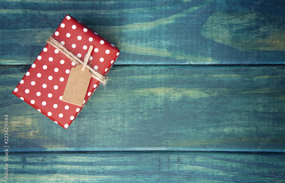 Obraz premium Single Wrapped Christmas Present with Gift Tag on a Wooden Table