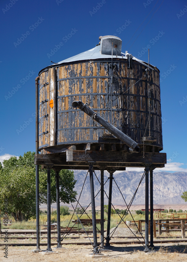 A historic wooden water tank stands along the tracks in an old narrow